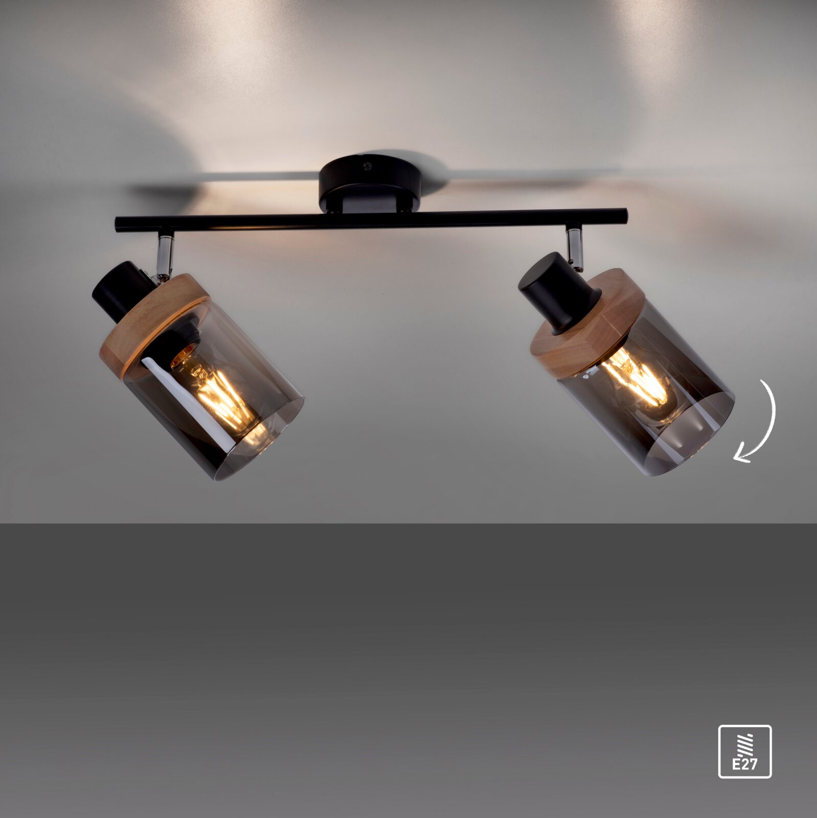 Zweiflammige Decken-Spotleuchte in Schwarz mit Holzdetails und rauchgrauen Glaszylindern, warm leuchtende E27-Leuchtmittel, fotografiert aus Untersicht von unten zur Decke.