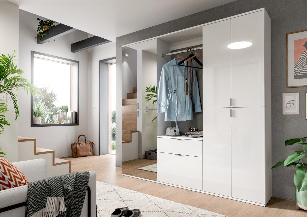 Moderner weißer Hochschrank mit glänzender Oberfläche, teilweise geöffnet, zeigt Innenraum mit Kleiderstange und Schubladen, Perspektive von schräg vorne.