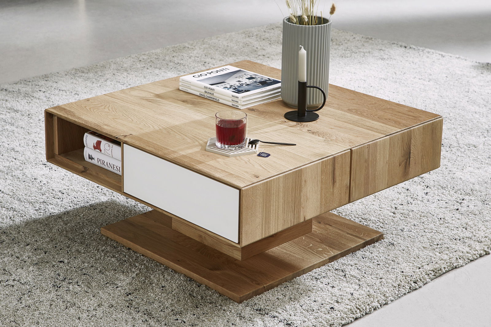 Moderner Couchtisch aus Holz mit quadratischer Form, seitlichem Stauraum und dekorativen Gegenständen auf der Oberfläche, aus einer leicht erhöhten Perspektive fotografiert.