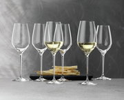 Sechs elegante Weißweinkelche der Serie Topline, teilweise gefüllt, auf einem Tisch mit Knabbergebäck im Hintergrund, seitliche Perspektive.