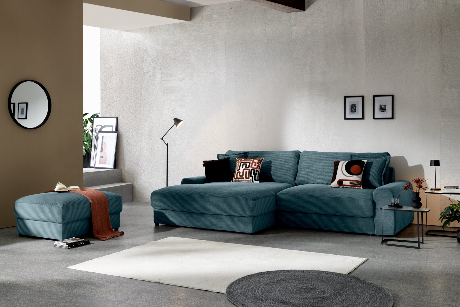 Türkises Cord-Ecksofa mit Ottomane und Zierkissen in modernem Wohnzimmer, Frontansicht aus leicht schräger Perspektive