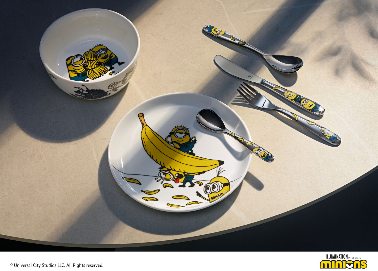 WMF Kinderbesteck-Set 4-tlg. Minions Kinderbesteck-Set mit Minions-Motiven, bestehend aus Teller, Schüssel und Besteck, aus der Vogelperspektive fotografiert.
