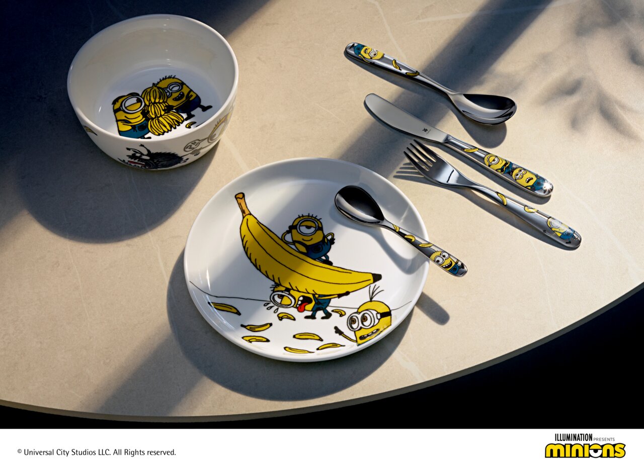Kinderbesteck-Set mit Minions-Motiven, bestehend aus Teller, Schüssel und Besteck, aus der Vogelperspektive fotografiert.