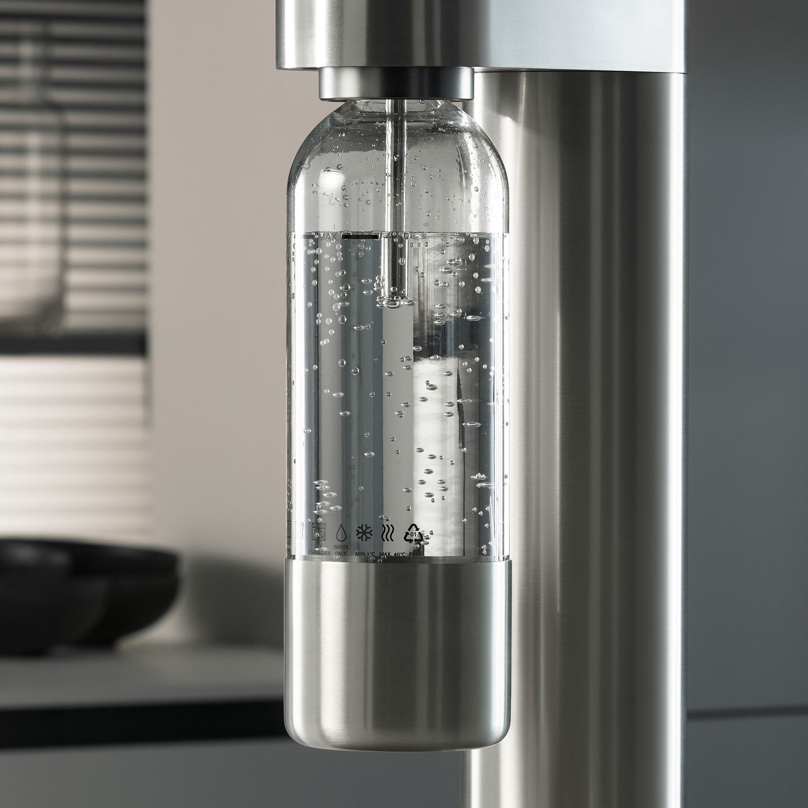 Nahaufnahme einer modernen Wasserflasche in einem Wassersprudler, gefüllt mit sprudelndem Wasser, in einer stilvollen Küchenumgebung.