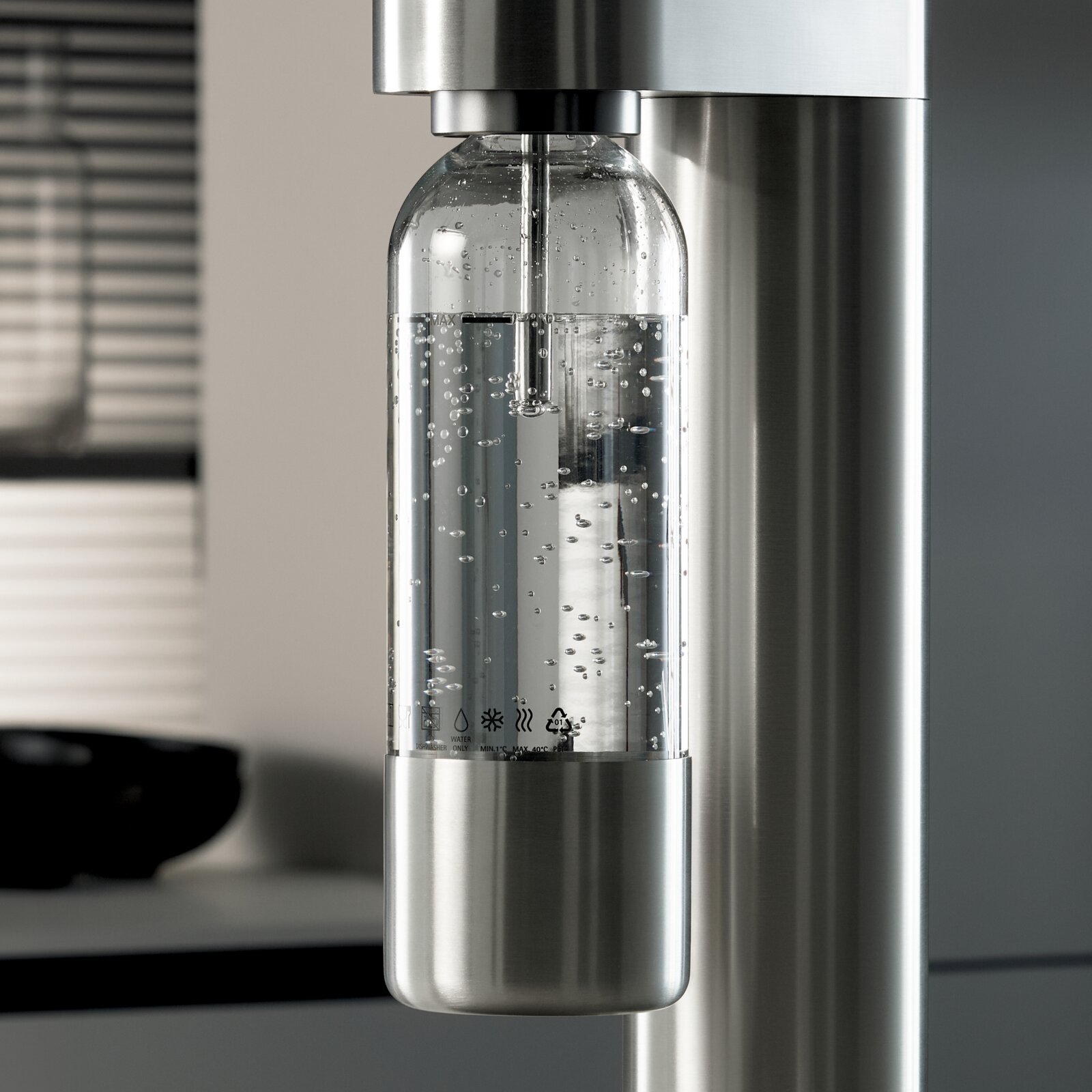 Nahaufnahme einer modernen Wasserflasche in einem Wassersprudler, gefüllt mit sprudelndem Wasser, in einer stilvollen Küchenumgebung.