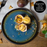 Dessertteller in Blau-Braun mit kunstvoll angerichtetem Dessert, aus der Vogelperspektive fotografiert.