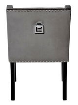 Rückansicht eines grauen Stuhls mit Nietenverzierung und quadratischem Griff an der Rückenlehne.