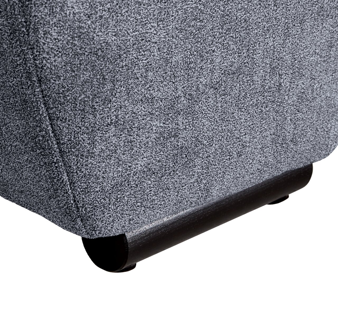 Nahaufnahme der unteren Ecke eines grauen Big-Sofas mit schwarzem Fuß, seitliche Perspektive.