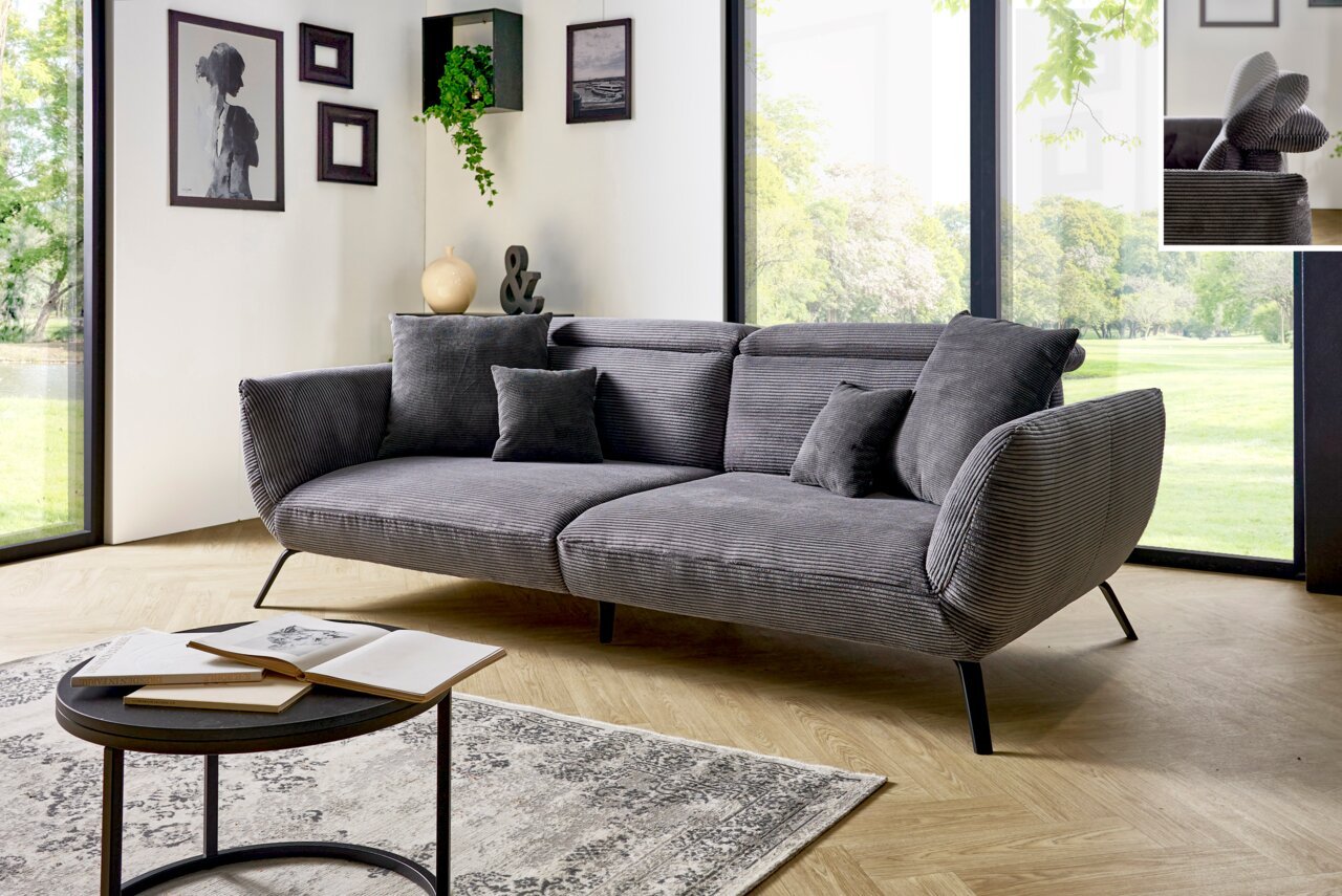Graues Megasofa mit Kissen in modernem Wohnzimmer, seitliche Perspektive