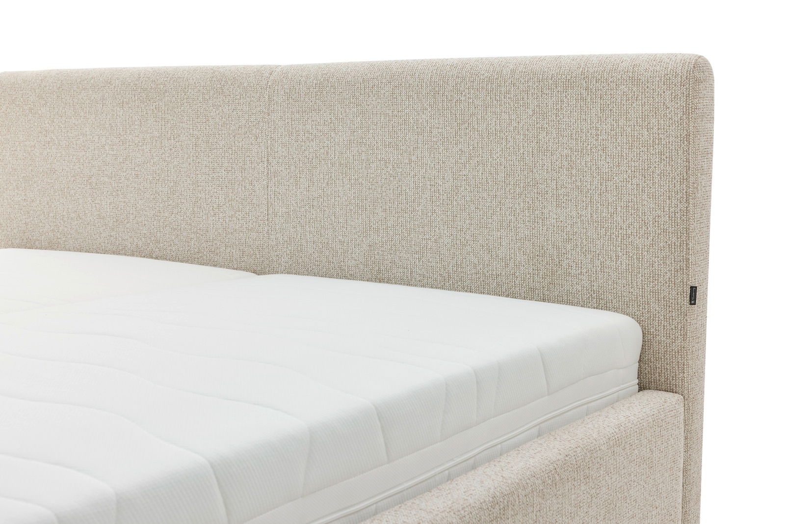 Nahaufnahme eines Polsterbetts mit beigem Stoffbezug und weißer Matratze, seitliche Perspektive