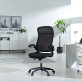 Moderner schwarzer Drehstuhl mit Netzrückenlehne und Armlehnen, seitliche Perspektive in einem hellen Büro mit Pflanzen und Dekoration.