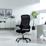 Moderner schwarzer Drehstuhl mit Netzrückenlehne und Armlehnen, seitliche Perspektive in einem hellen Büro mit Pflanzen und Dekoration.