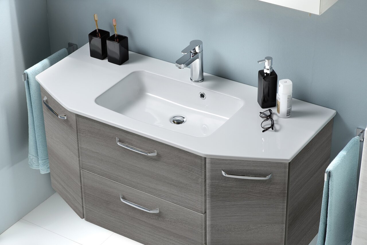 Modernes Badezimmer-Waschtisch-Set mit weißem Aufsatzwaschbecken, verchromter Armatur und grauem Unterschrank mit Schubladen, fotografiert in schräger Frontansicht von oben