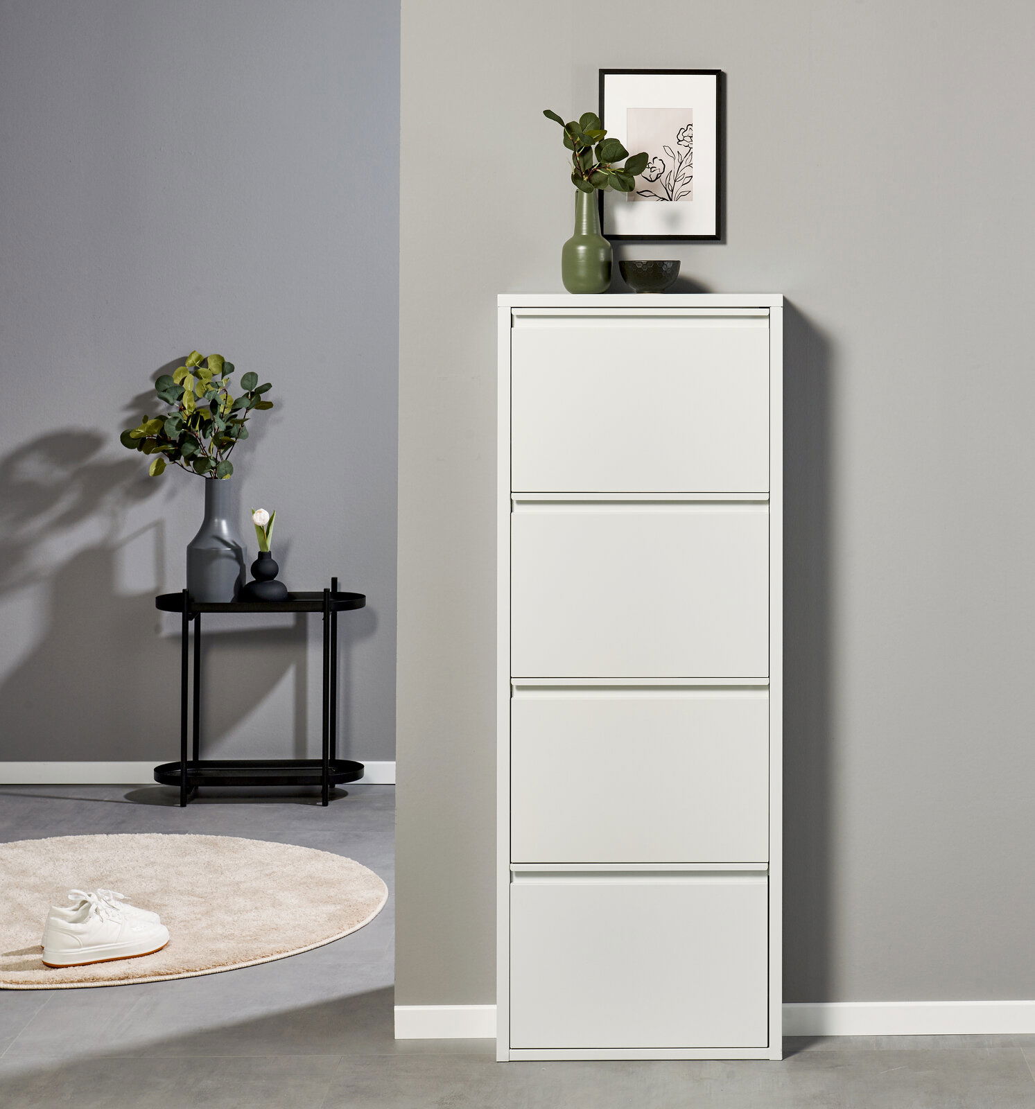 Weißer, hoher Schuhschrank mit vier Klappfächern in moderner Wohnszene, frontal aus leicht erhöhter Perspektive fotografiert