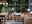 Wohnlicher Wintergarten mit Rattan-Sesseln, Beistelltisch mit Blumenstrauß und dekorativer Beleuchtung.