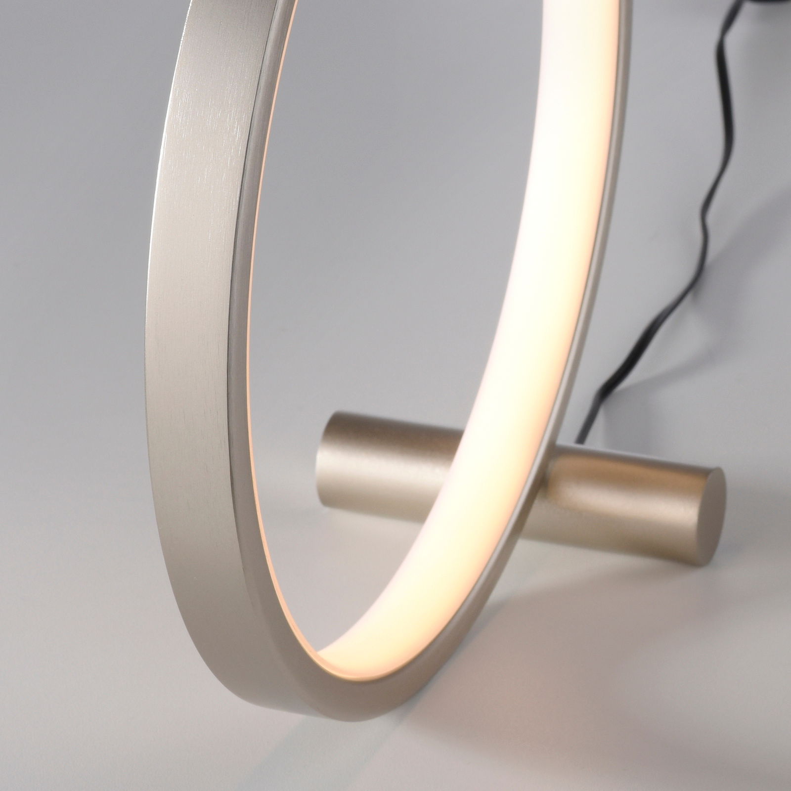 Nahaufnahme einer modernen Tischleuchte MINI RITUS in Ringform mit warmem Licht, seitliche Perspektive