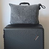 Graue Reisedecke in einer Tasche auf einem schwarzen Koffer, Vorderansicht
