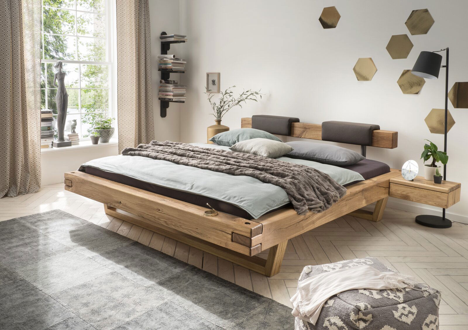 Modernes Balkenbett aus Holz in einem stilvoll eingerichteten Schlafzimmer, seitliche Perspektive