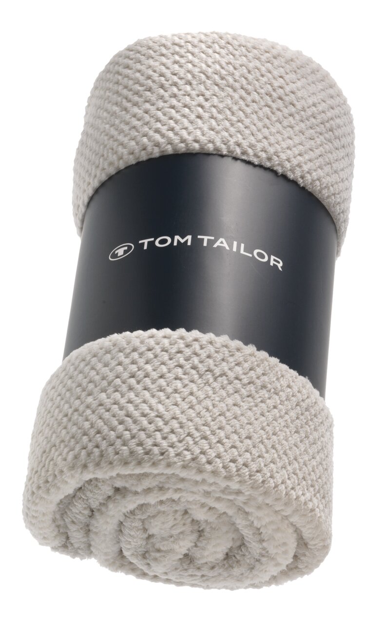 Beige gestricktes Plaid von Tom Tailor, zusammengerollt und von vorne fotografiert.