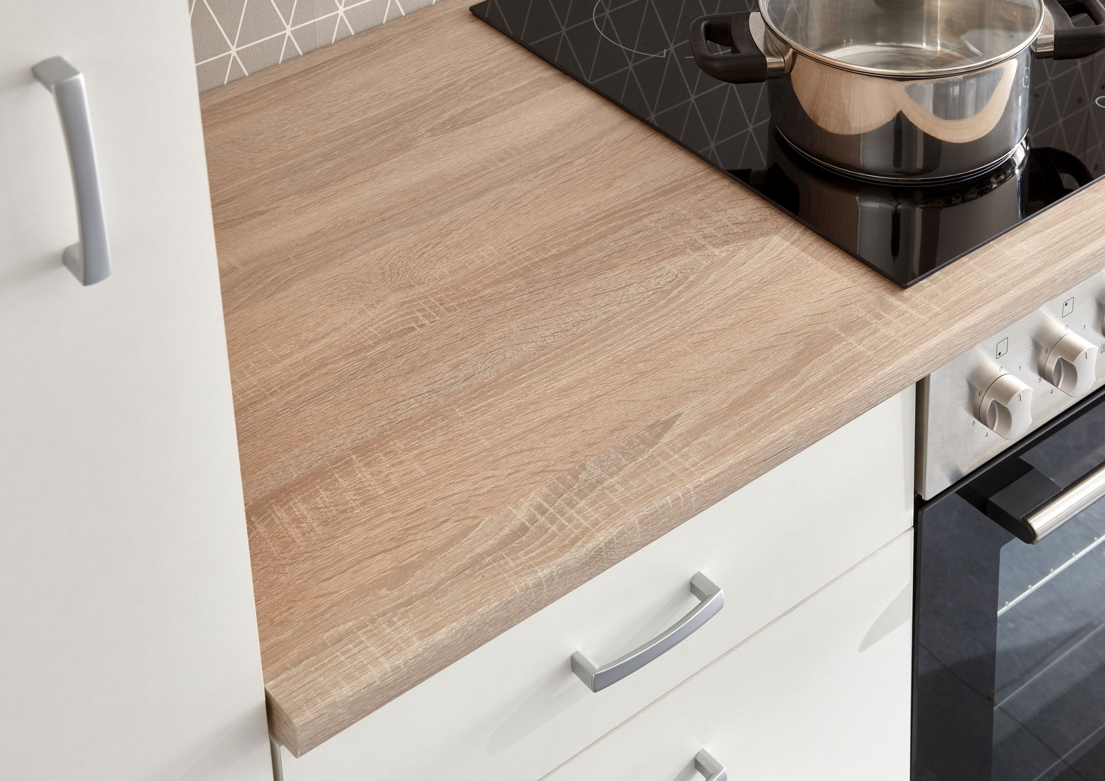 Nahaufnahme einer Küchenarbeitsplatte in Holzoptik mit einem Kochfeld und einem Topf, seitliche Perspektive.
