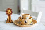 Kinder-Set 3-tlg. Connect Zoo mit Tiermotiven, bestehend aus Teller, Schüssel und Becher, auf einem Tisch mit einem Stofflöwen im Hintergrund, seitliche Perspektive