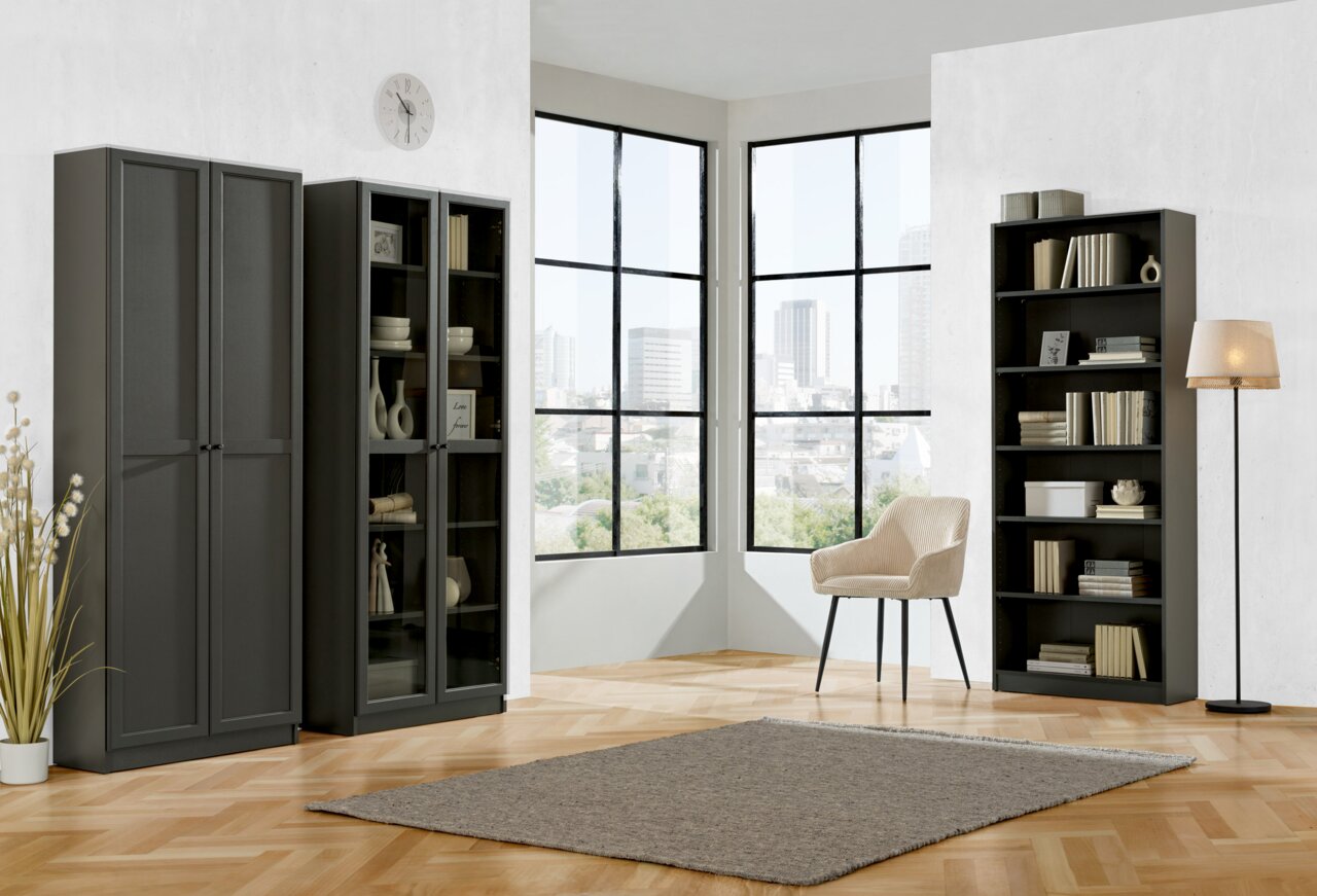 Carryhome Regal MILLY Moderne Wohnzimmeransicht mit drei schwarzen Regalen, einem Sessel und einer Stehlampe vor großen Fenstern mit Stadtblick.