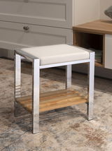 Moderner Hocker mit weißem Sitzpolster und Metallrahmen, darunter eine Holzablage. Perspektive: seitliche Ansicht.