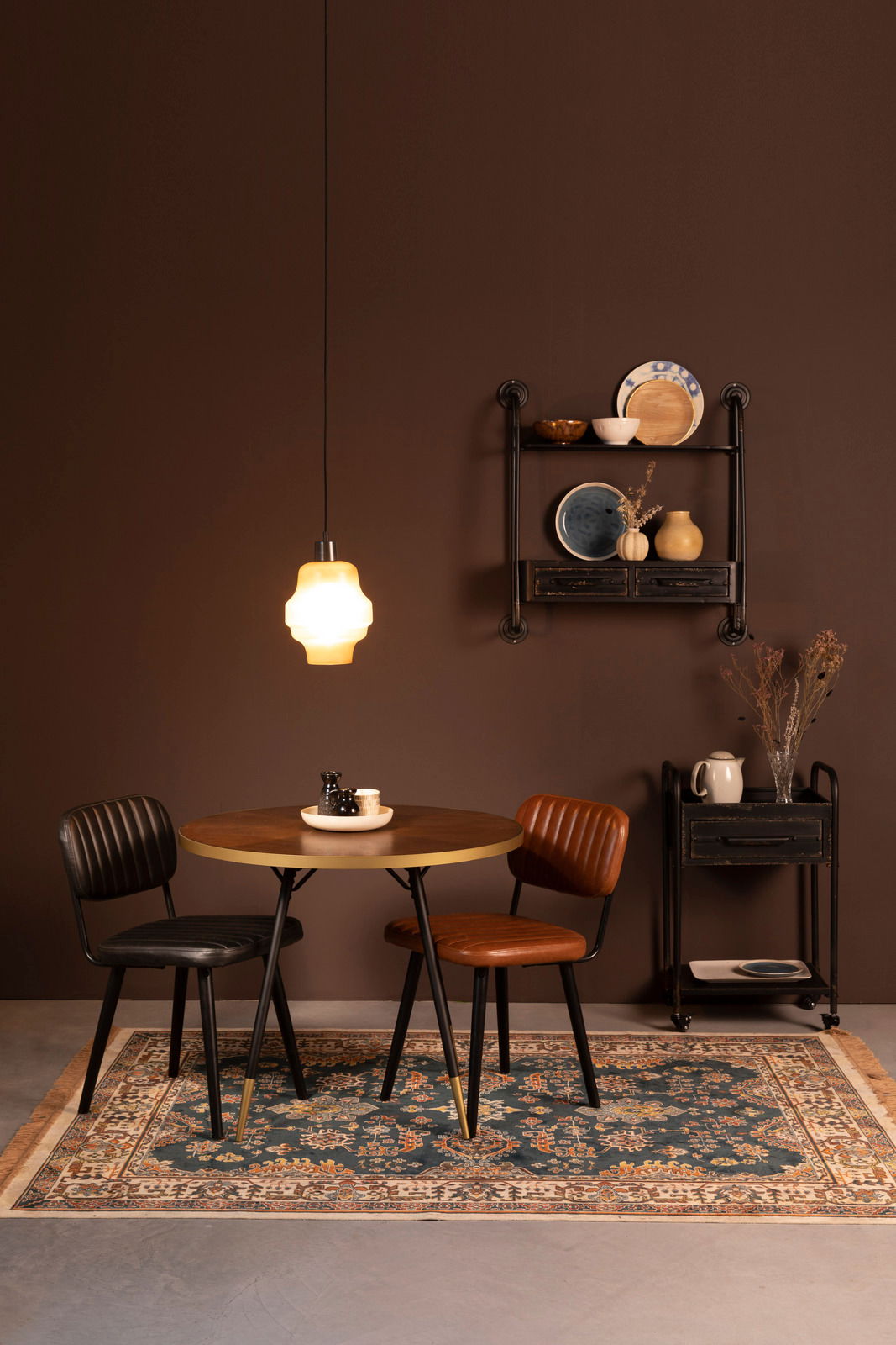 Ein stilvoll eingerichteter Raum mit einem runden Holztisch, zwei Stühlen und einem dekorativen Teppich in einem warmen, gemütlichen Ambiente. Der Teppich ist im Vordergrund zu sehen.
