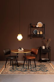 Ein stilvoll eingerichteter Raum mit einem runden Holztisch, zwei Stühlen und einem dekorativen Teppich in einem warmen, gemütlichen Ambiente. Der Teppich ist im Vordergrund zu sehen.