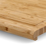 Nahaufnahme eines Back- und Tranchierbretts aus Holz mit abgerundeten Kanten, perspektivisch von der Seite aufgenommen.