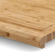 Nahaufnahme eines Back- und Tranchierbretts aus Holz mit abgerundeten Kanten, perspektivisch von der Seite aufgenommen.