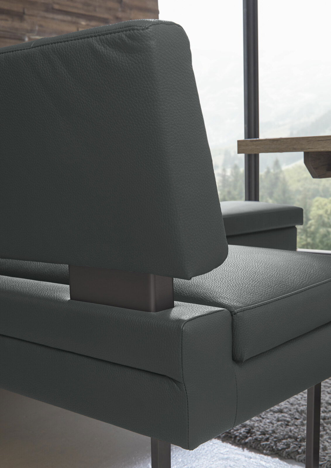 Detailansicht einer modernen Eckbank mit dunkelgrauem Lederbezug und Metallgestell, seitliche Perspektive.