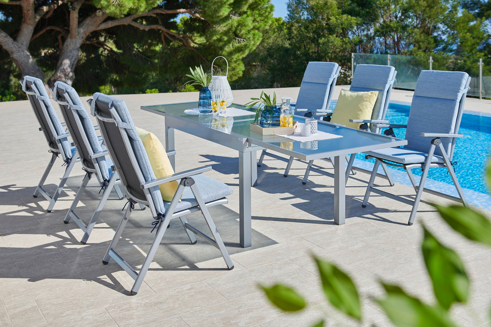 Klappsessel in einer stilvollen Outdoor-Essgruppe am Pool, seitliche Perspektive