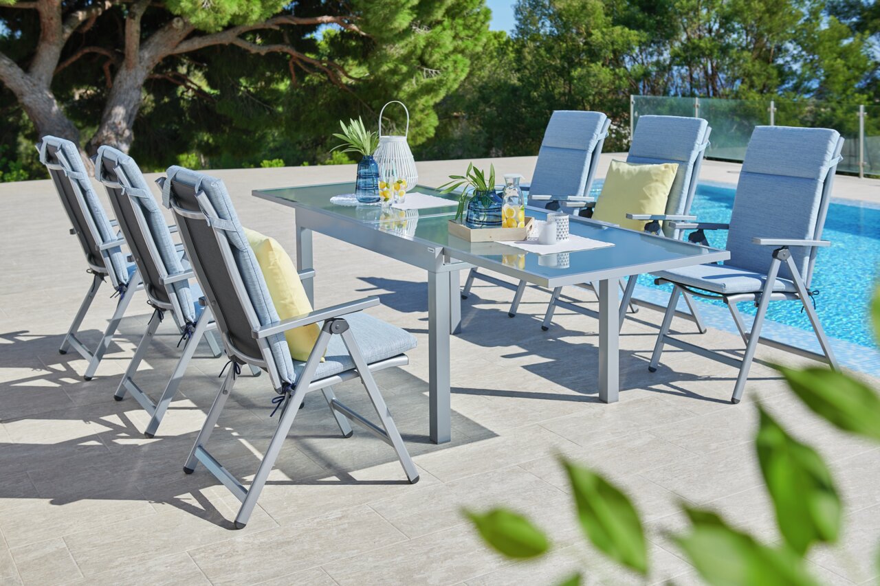 Klappsessel in einer stilvollen Outdoor-Essgruppe am Pool, seitliche Perspektive