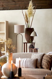 Moderner Wohnraum mit einem Lampenschirm Zylinder 40-40-30 auf einem eleganten Stehlampenständer, umgeben von stilvollen Dekorationen und gemütlichen Möbeln. Perspektive von vorne.