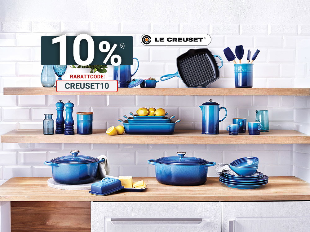 Le Creuset Küchenserie in Blau stilvoll auf offenen Holzregalen präsentiert