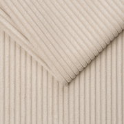 Close-up van een beige, geribbelde stof in diagonaal perspectief.