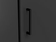 Nahaufnahme eines schwarzen Griffs an einer dunklen Schranktür, seitliche Perspektive.