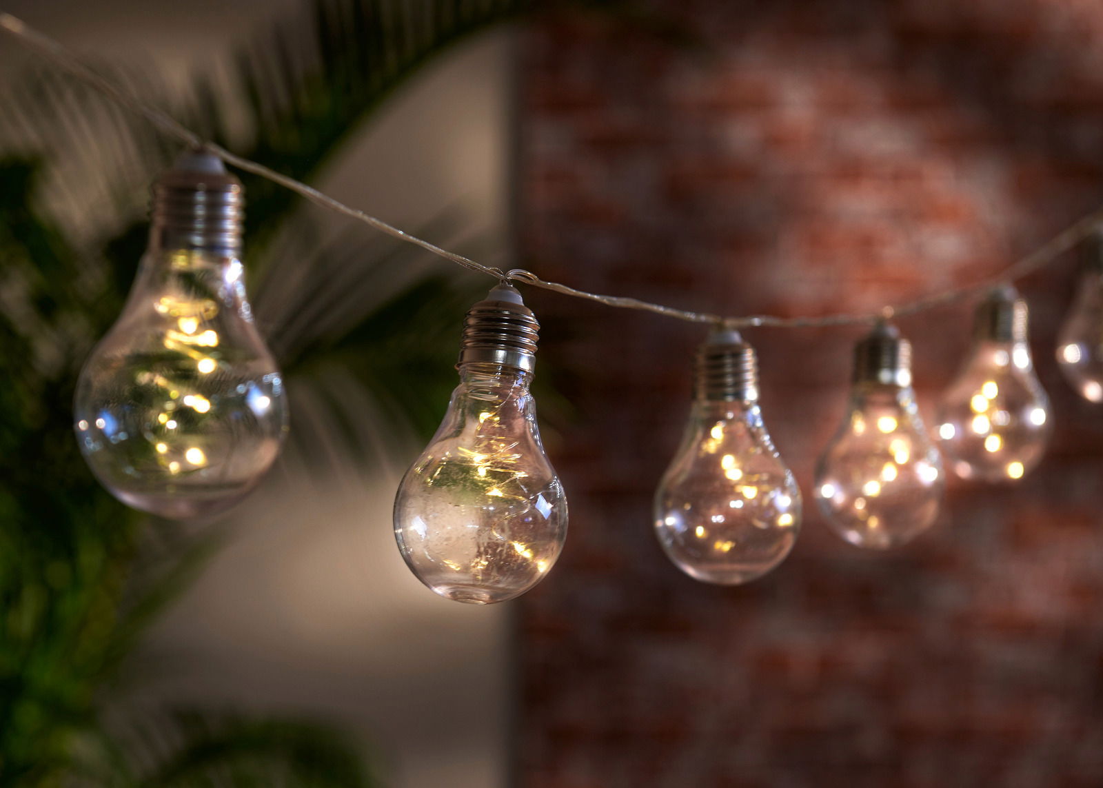 Lichterkette mit Glühbirnen-Design, beleuchtet in einer gemütlichen Abendatmosphäre, seitliche Perspektive
