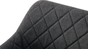 Detailaufnahme der Rückenlehne eines dunkelgrauen, stoffbezogenen Stuhls mit rautenförmiger Steppung, schräg von vorne oben fotografiert