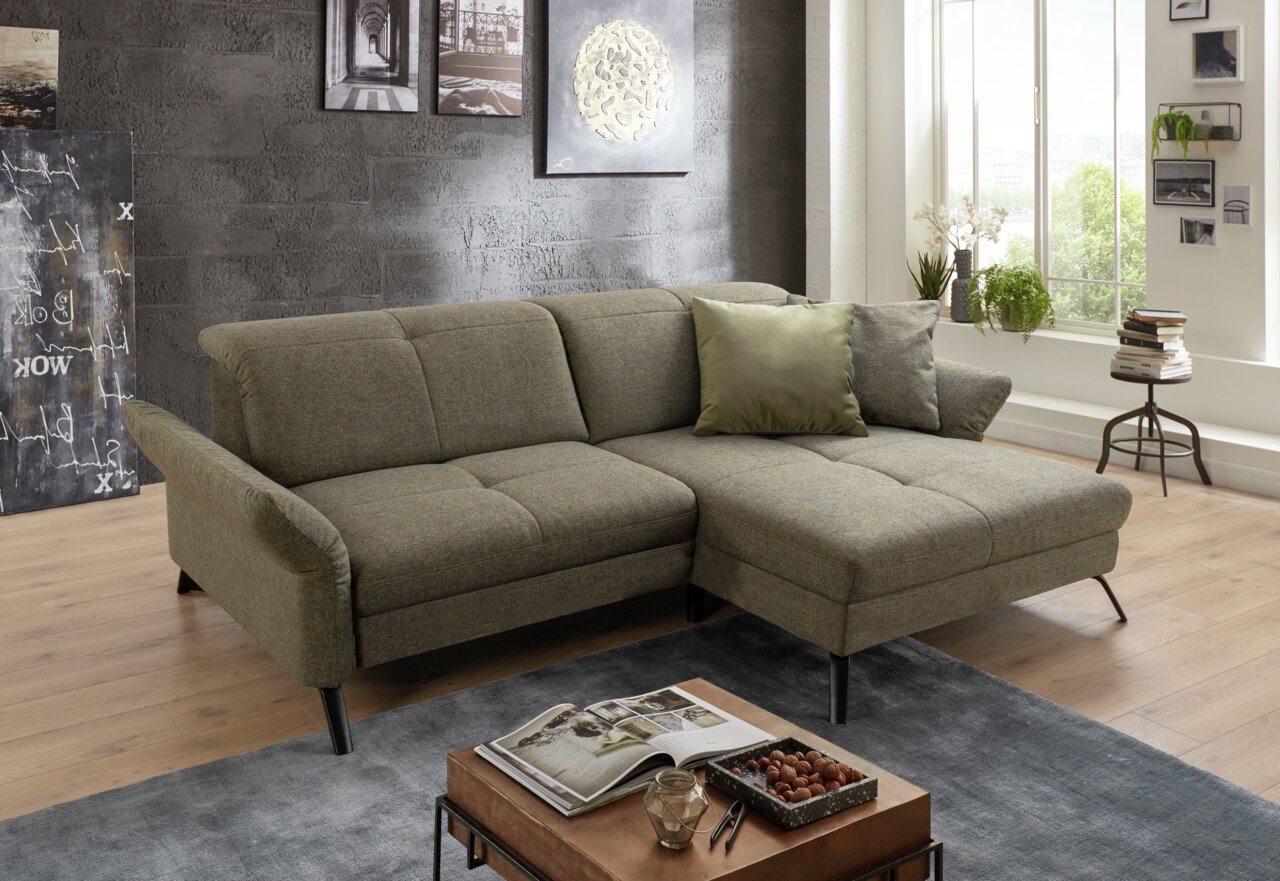 Gezellige hoekbank in een moderne woonkamer, gezien vanaf de zijkant, met grijze stoffen bekleding en decoratieve kussens.