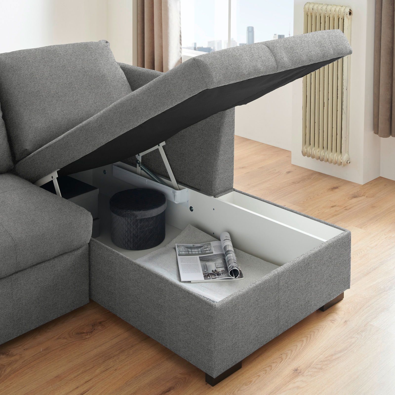 Graues Ecksofa mit geöffneter Stauraumfunktion, seitliche Perspektive