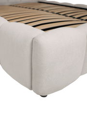 Nahaufnahme eines weißen Polsterbettgestells mit Holzlattenrost, seitliche Perspektive