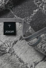 Nahaufnahme eines grauen Gästetuchs mit geometrischem Muster und einem schwarzen Etikett mit der Aufschrift 'JOOP!'