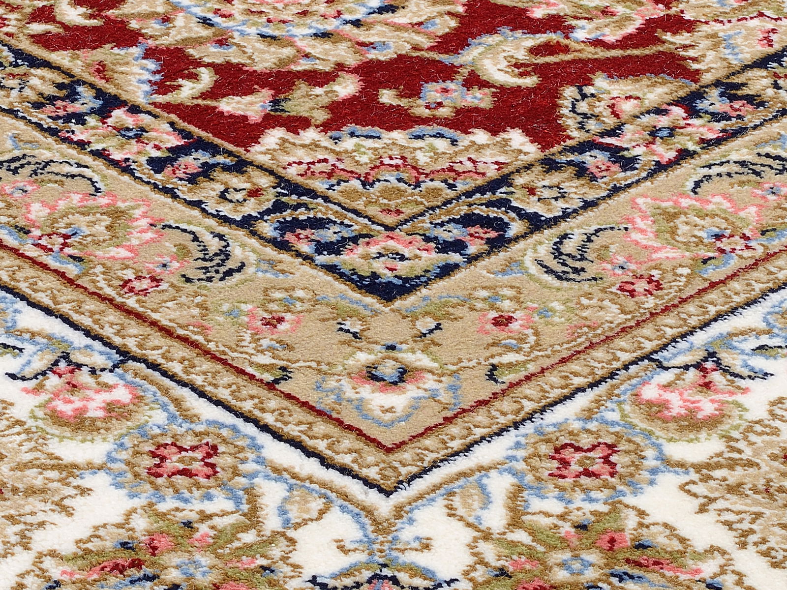 Nahaufnahme eines Orientteppichs mit traditionellem Keshan-Muster in Rot, Blau und Beige, schräg von oben fotografiert.