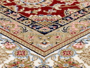 Nahaufnahme eines Orientteppichs mit traditionellem Keshan-Muster in Rot, Blau und Beige, schräg von oben fotografiert.