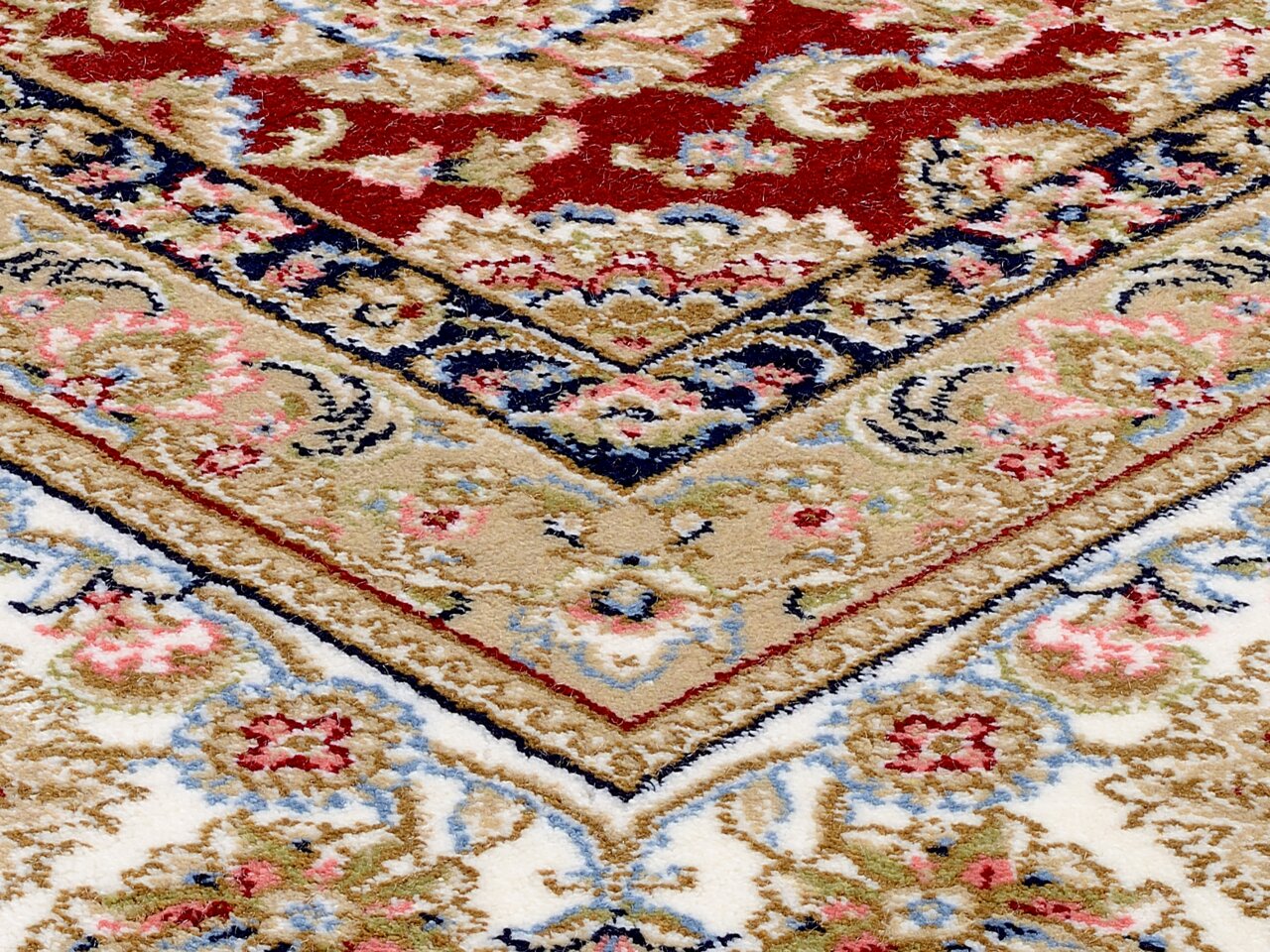 Nahaufnahme eines Orientteppichs mit traditionellem Keshan-Muster in Rot, Blau und Beige, schräg von oben fotografiert.