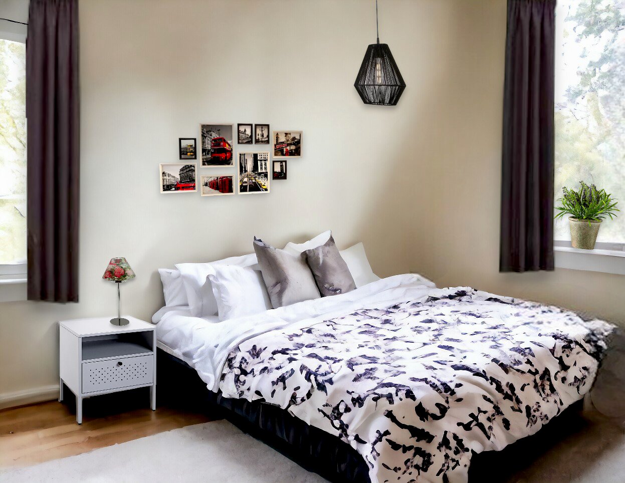 Modernes Schlafzimmer mit Doppelbett, weißer Bettwäsche mit schwarz-grauem Muster, grauen Kissen, Nachttisch und Hängelampe; Frontansicht leicht schräg von links.