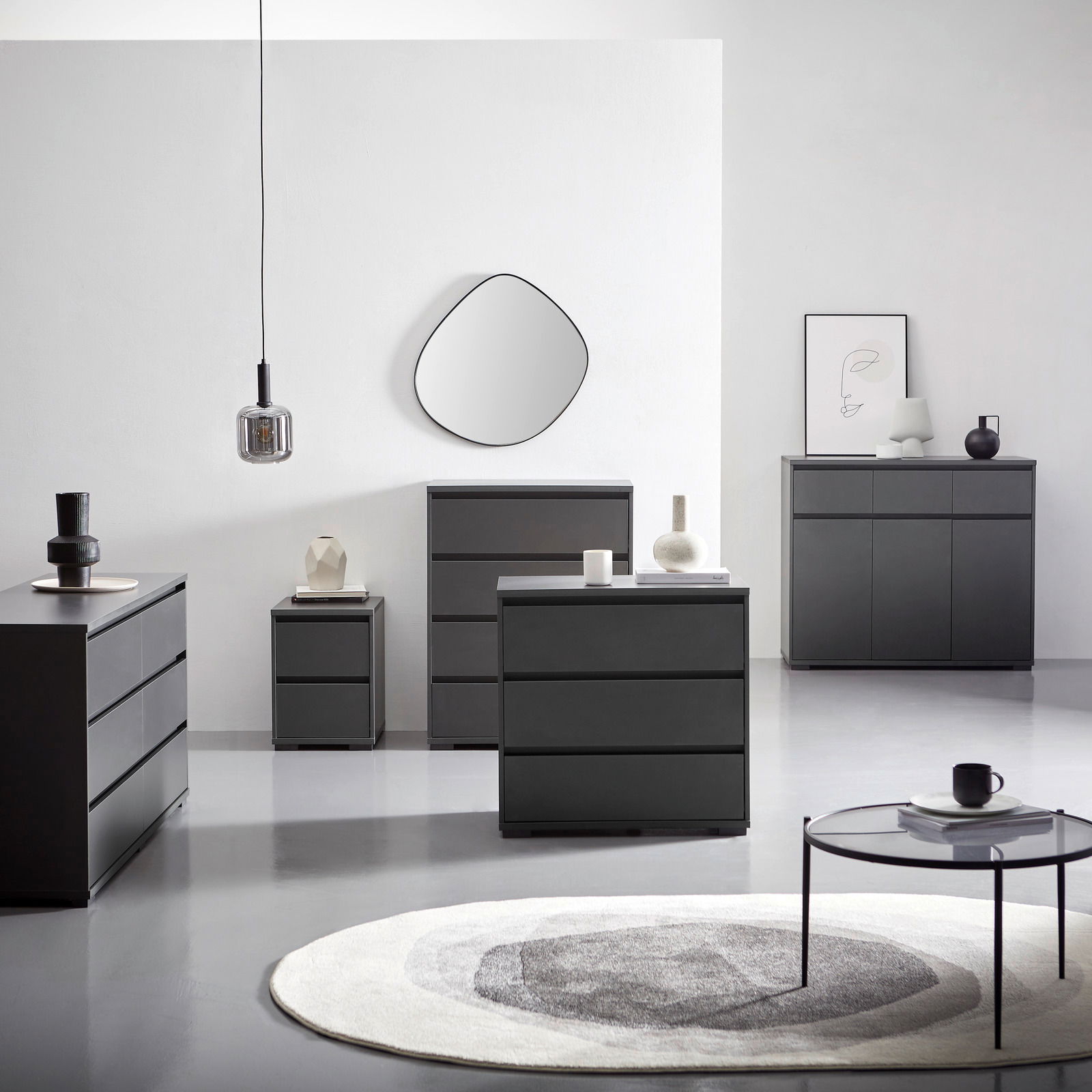 Carryhome Hochkommode LINE Moderne schwarze Kommoden und Sideboards in einem minimalistischen Raum, frontal und seitlich betrachtet, mit dekorativen Elementen und einem runden Teppich.