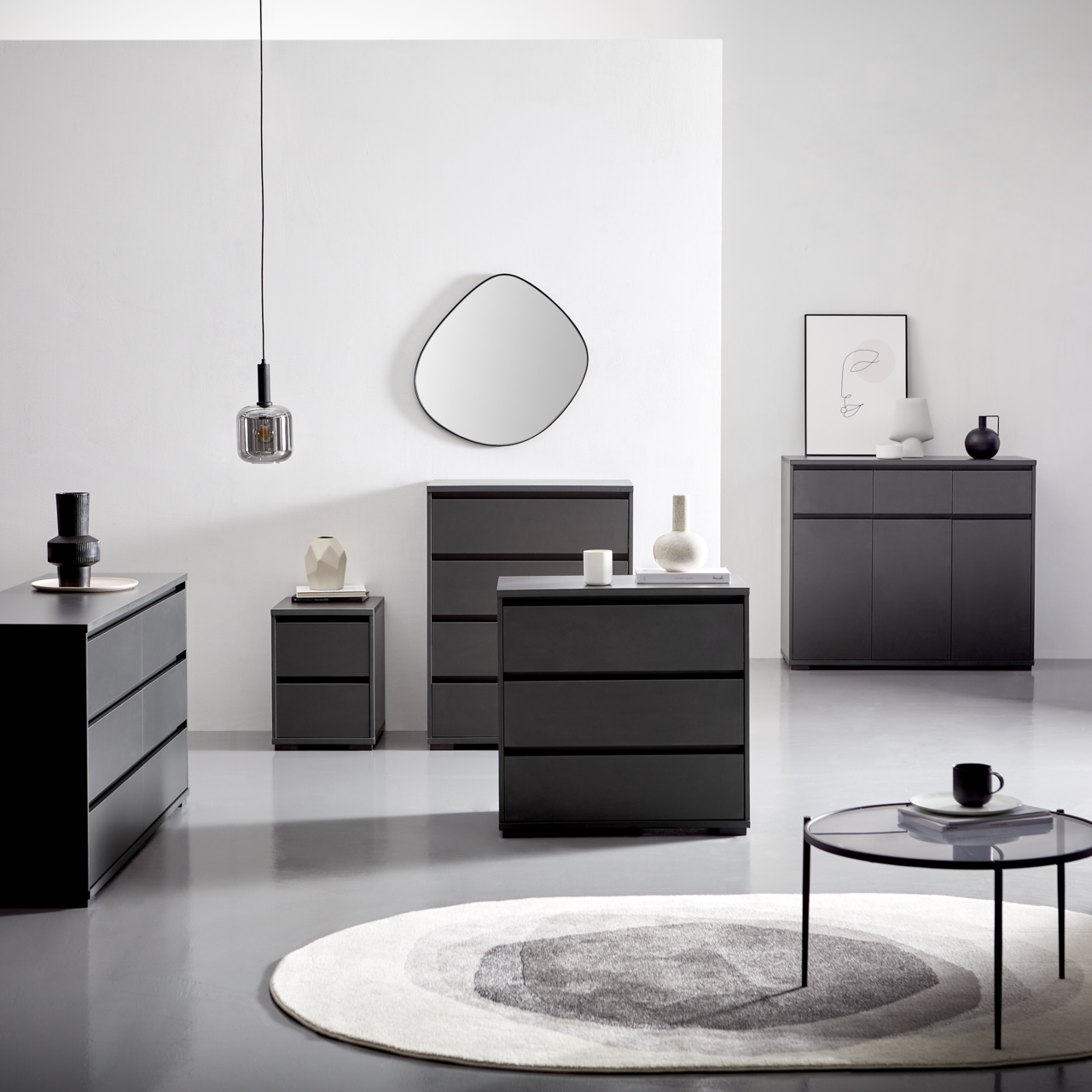 Carryhome Hochkommode LINE Moderne schwarze Kommoden und Sideboards in einem minimalistischen Raum, frontal und seitlich betrachtet, mit dekorativen Elementen und einem runden Teppich.